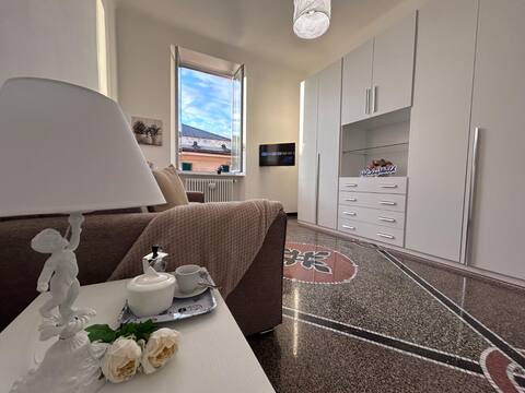 Soggiorno con pavimento in graniglia originale, armadio bianco e finestra con vista sui tetti di Sestri Ponente